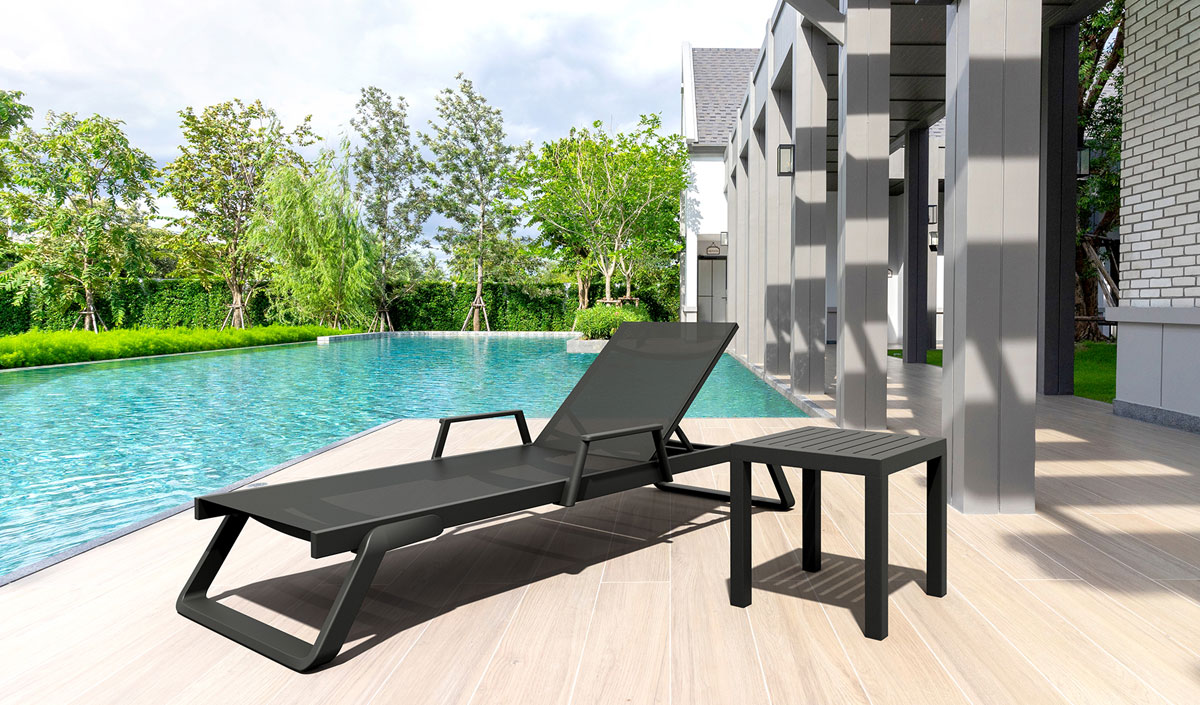 Chaise longue noire devant piscine avec table d'appoint