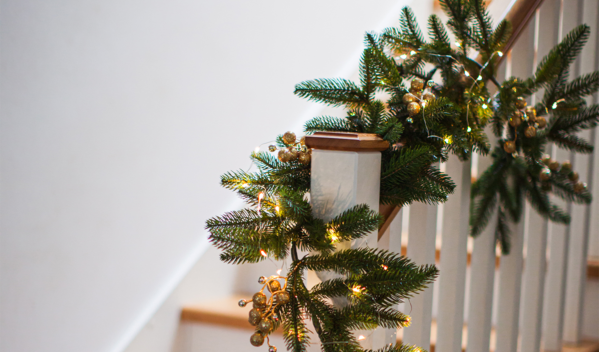 Décoration féérique dans le salon avec guirlande et branches de pin pour l'escalier